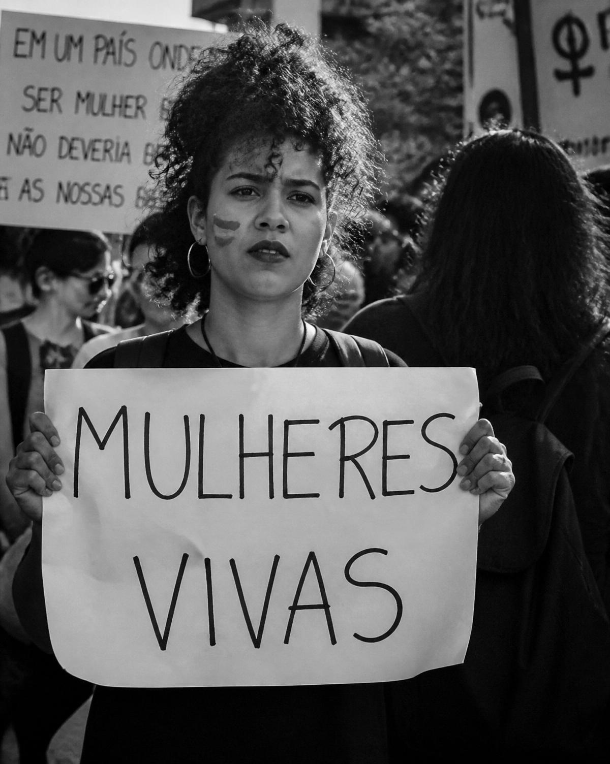 Jovem mulher em protesto segurando cartaz Mulheres Vivas