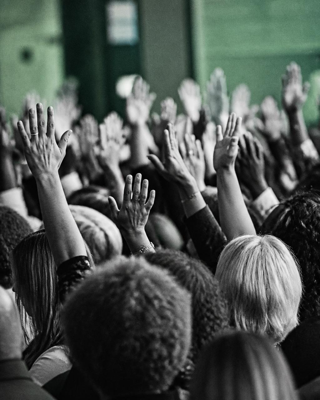 Mãos levantadas em assembleia simbolizando participação democrática